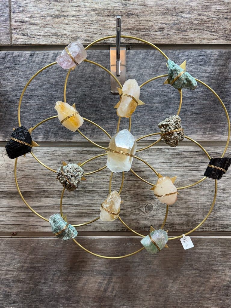 Flower-of-life wall piece with raw crystals wrapped in gold on reclaimed wood